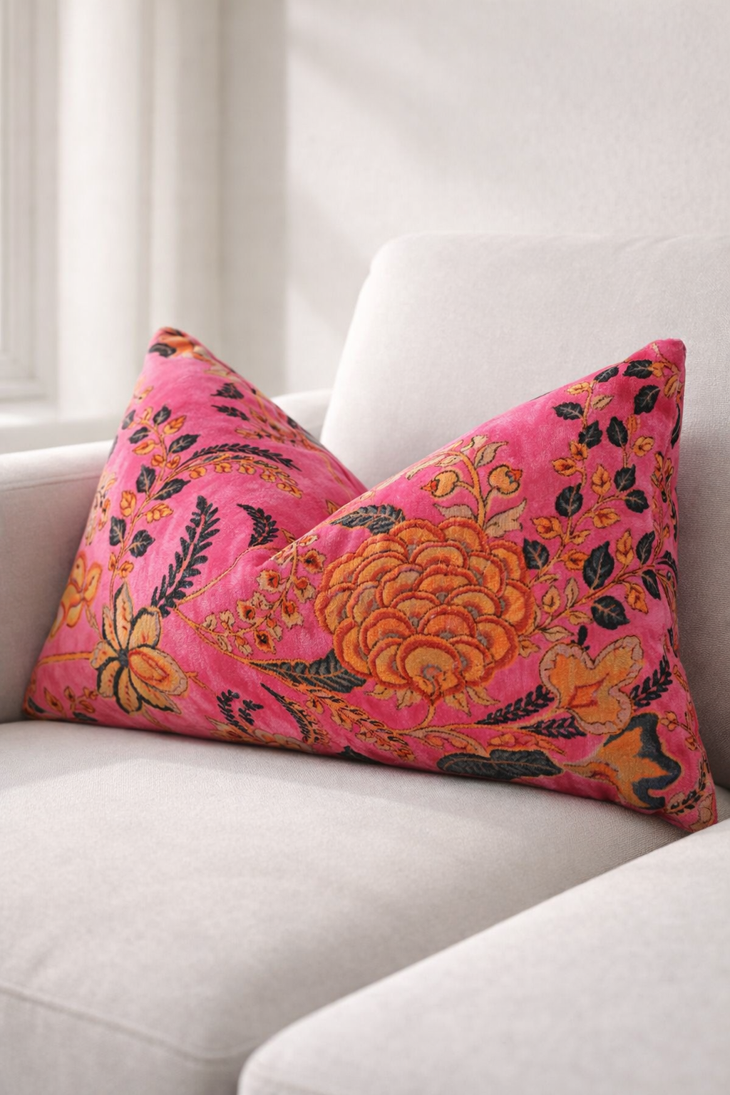 pink floral velvet cushion on bed with neutral pillows