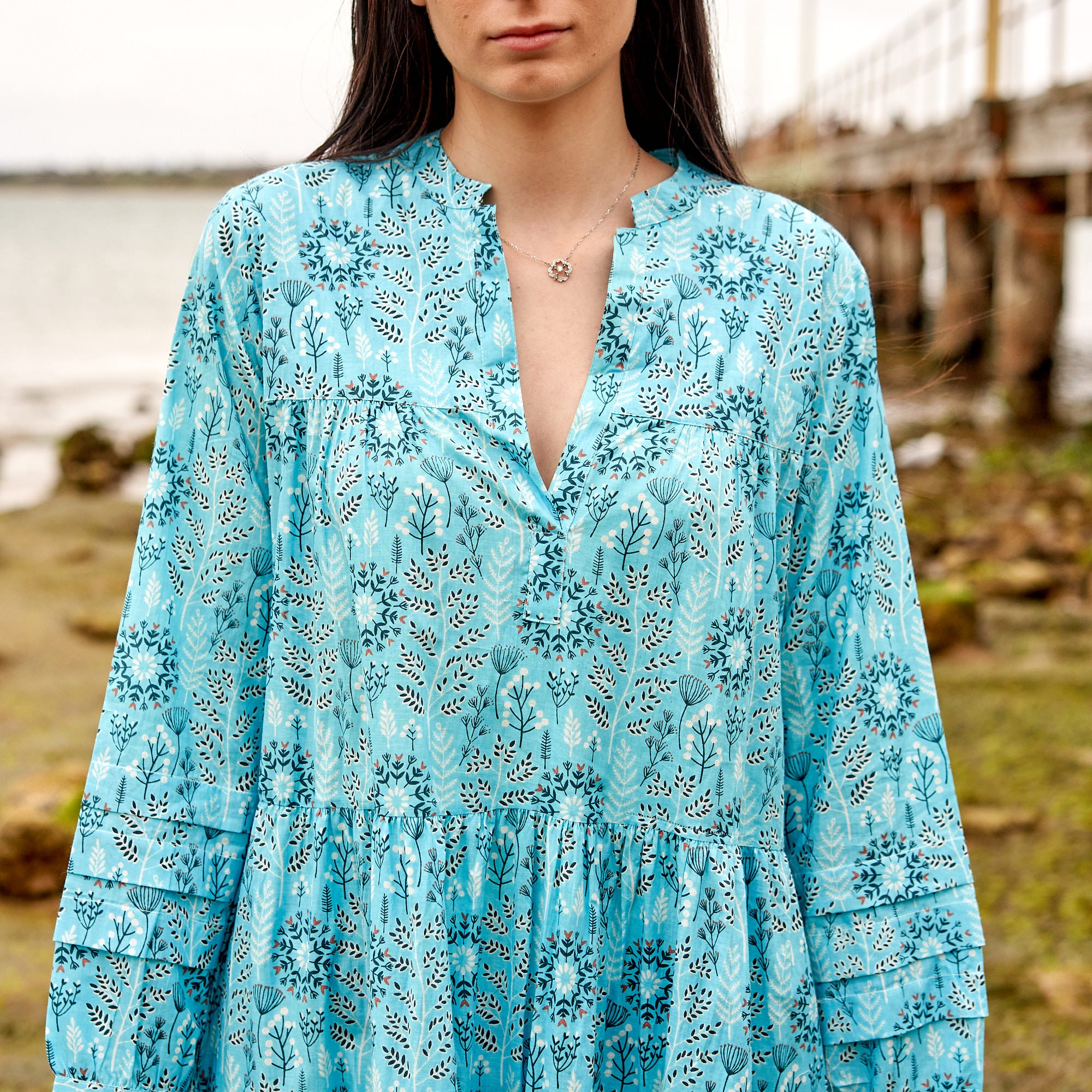 Coastal boho maxi dress with colourful floral print, vacation and beach outfit.
Cotton maxi dress with tiered flowy silhouette, relaxed summer fashion look.
