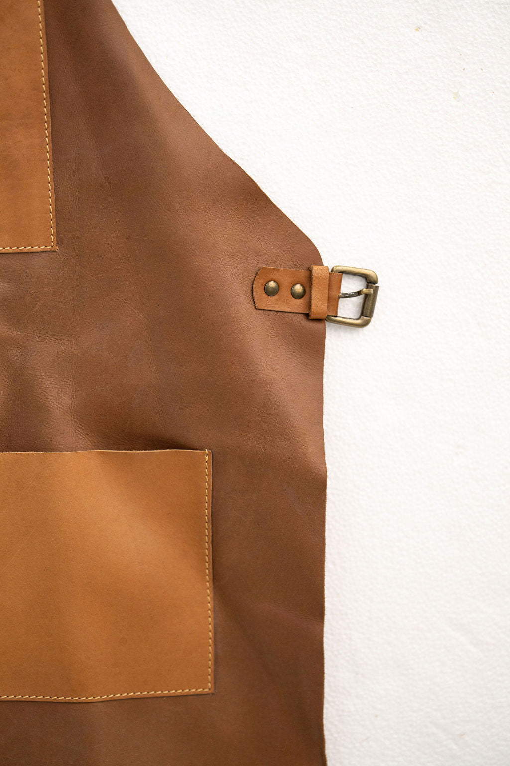 Tan leather apron close-up showing pocket design and premium finish