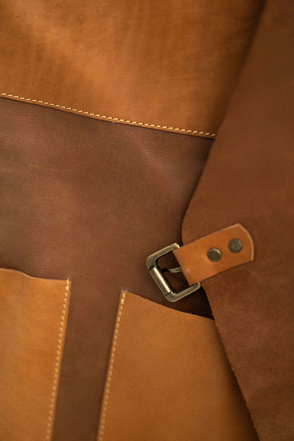 Tan leather apron worn by craftsman with pockets in workspace