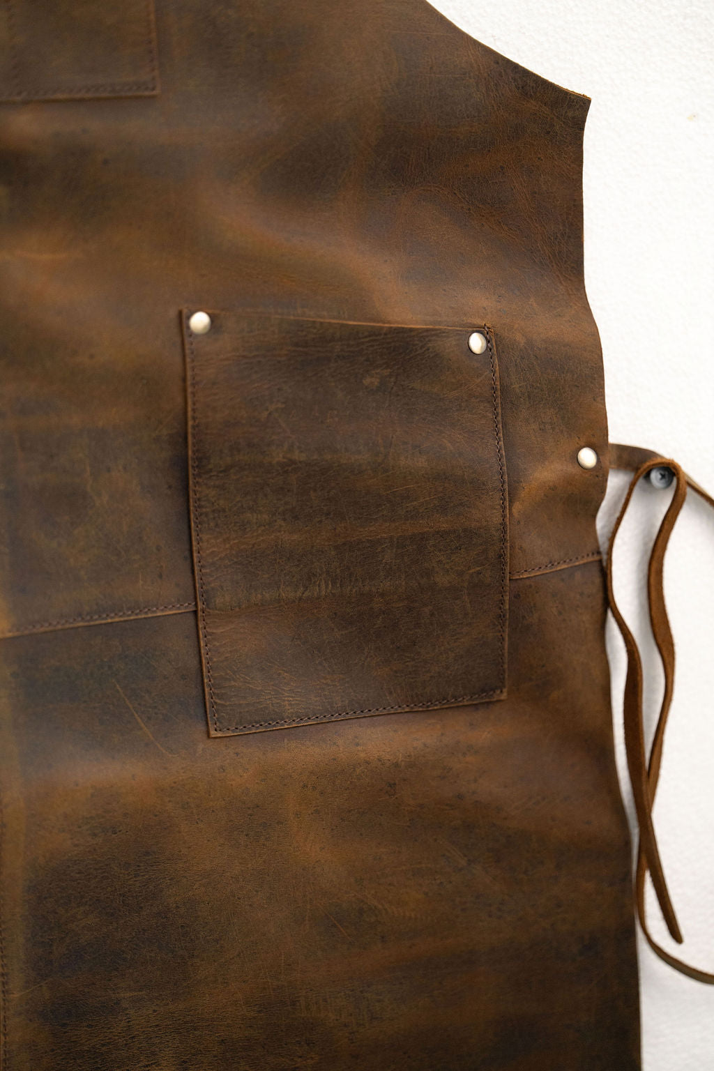 Brown leather apron close-up showing pockets and premium texture detail