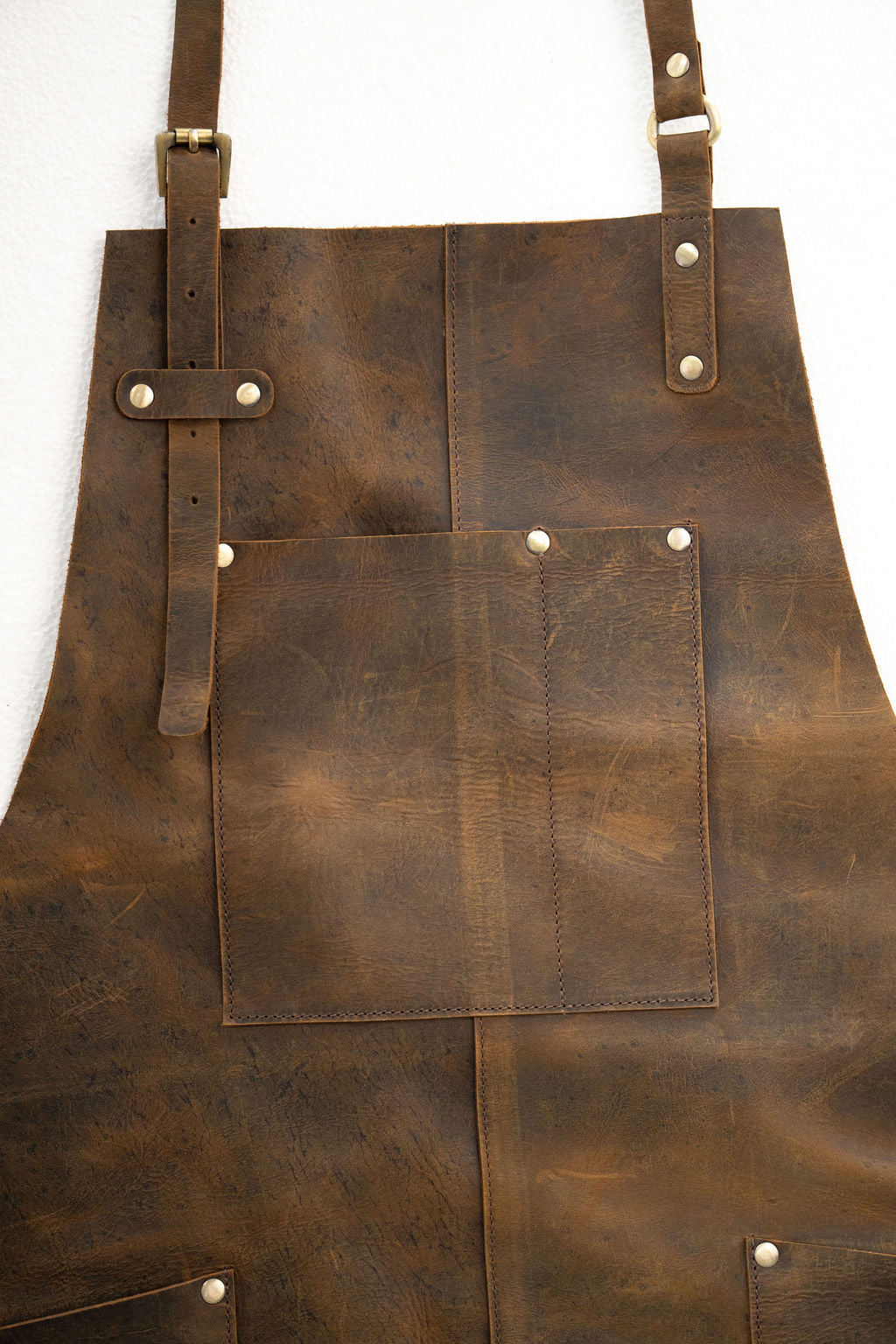 Back view of brown leather apron with adjustable straps and full length design