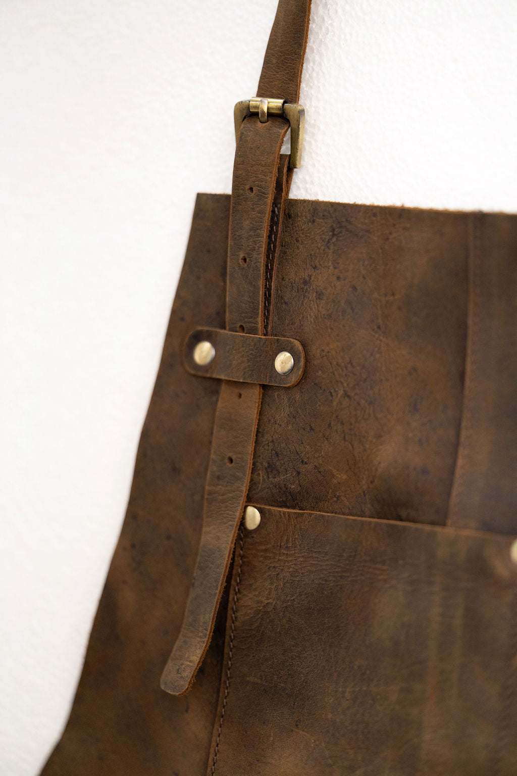 Brown leather apron worn by craftsman with tool pockets in workshop