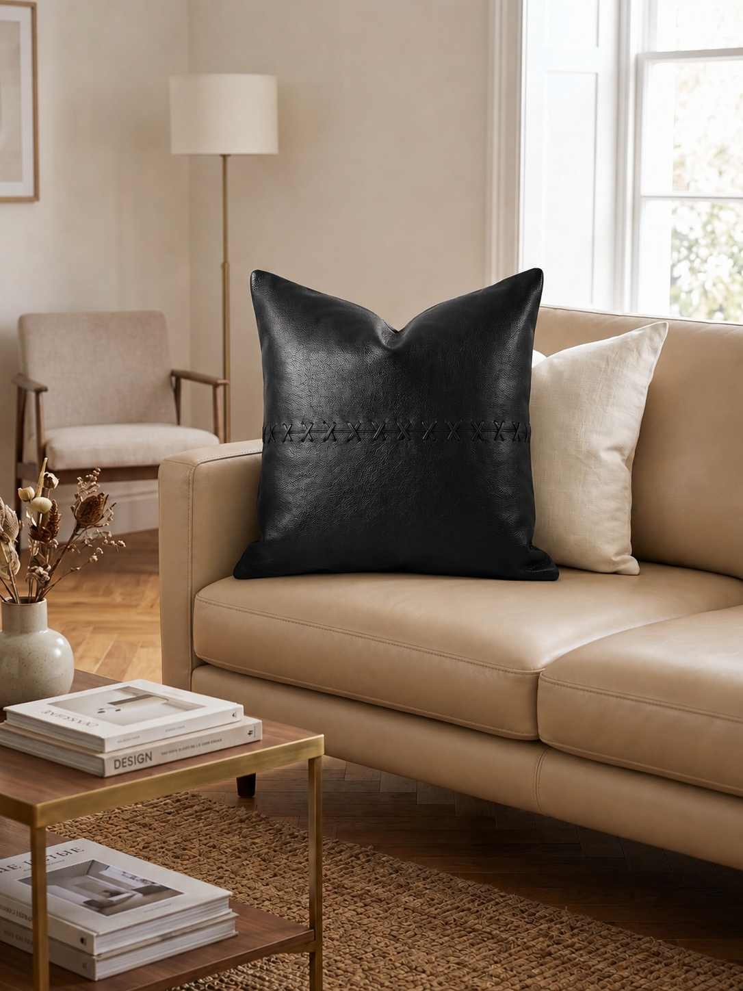 Black pillow on a beige sofa in a living room setting with books and a lamp.
