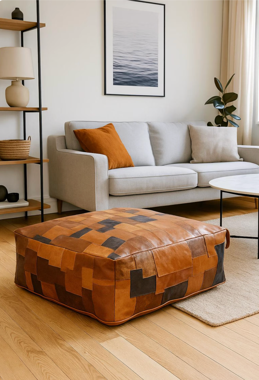Handcrafted tan leather patchwork pouffe ottoman with books on top in a cozy boho living room